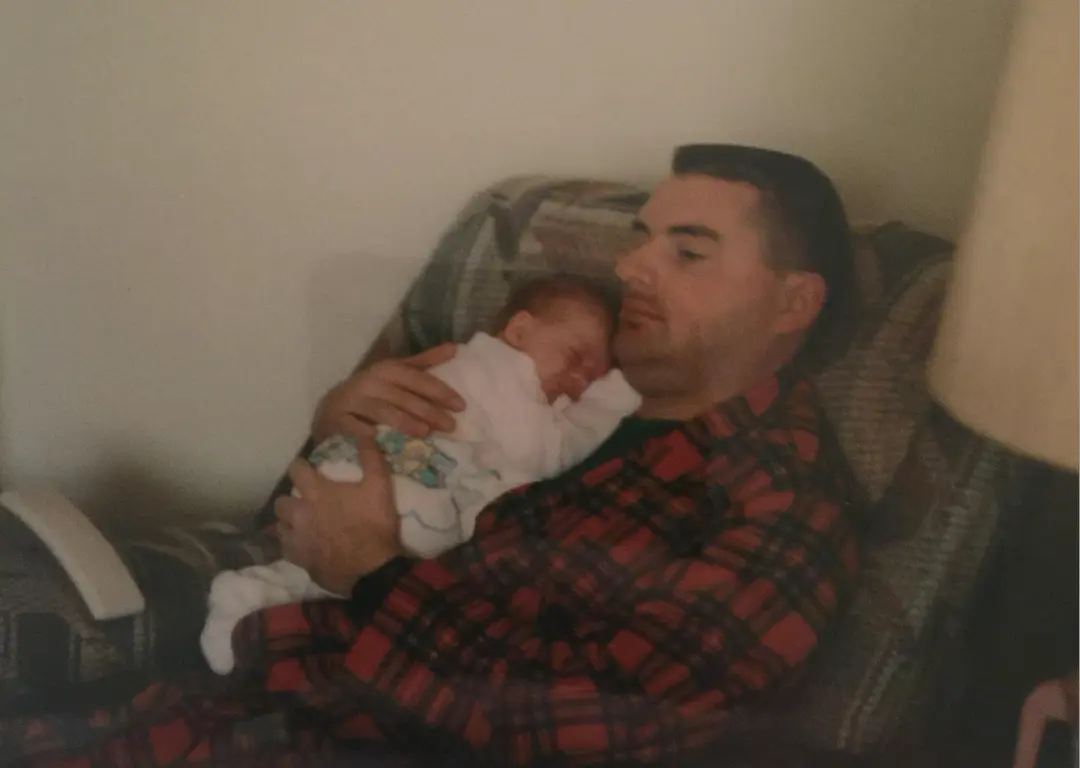 White male sits in chair whole holding his baby daughter