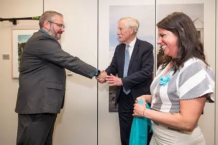 Lizzie smiling as two men shake hands at a lung cancer advocacy event.