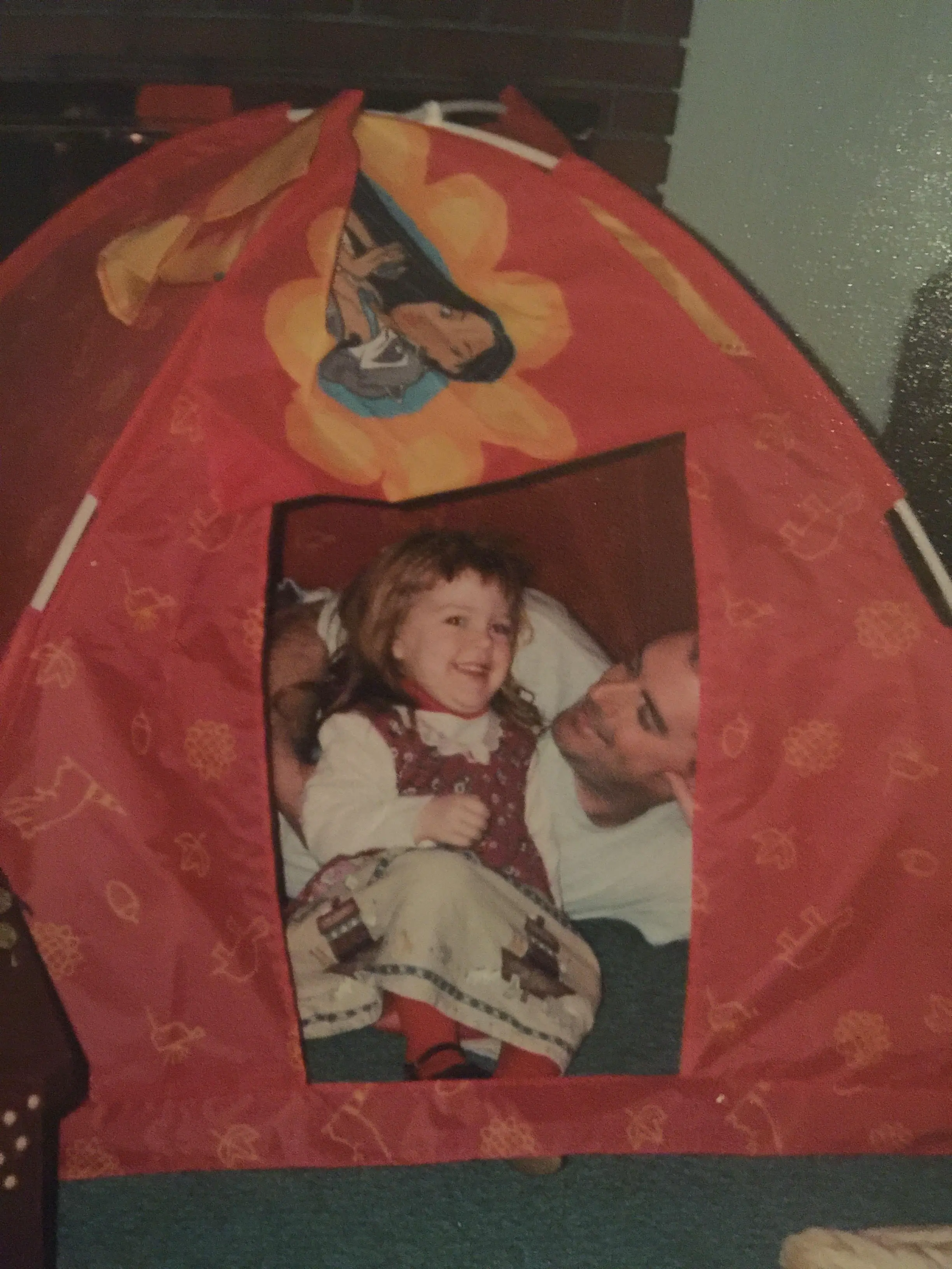 Girl toddler in orange Pocahontas tent with her doting father