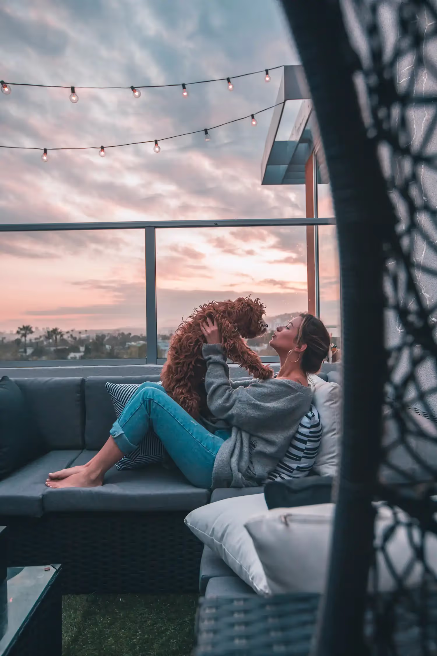 A woman kissing her dog on rooftop patio.