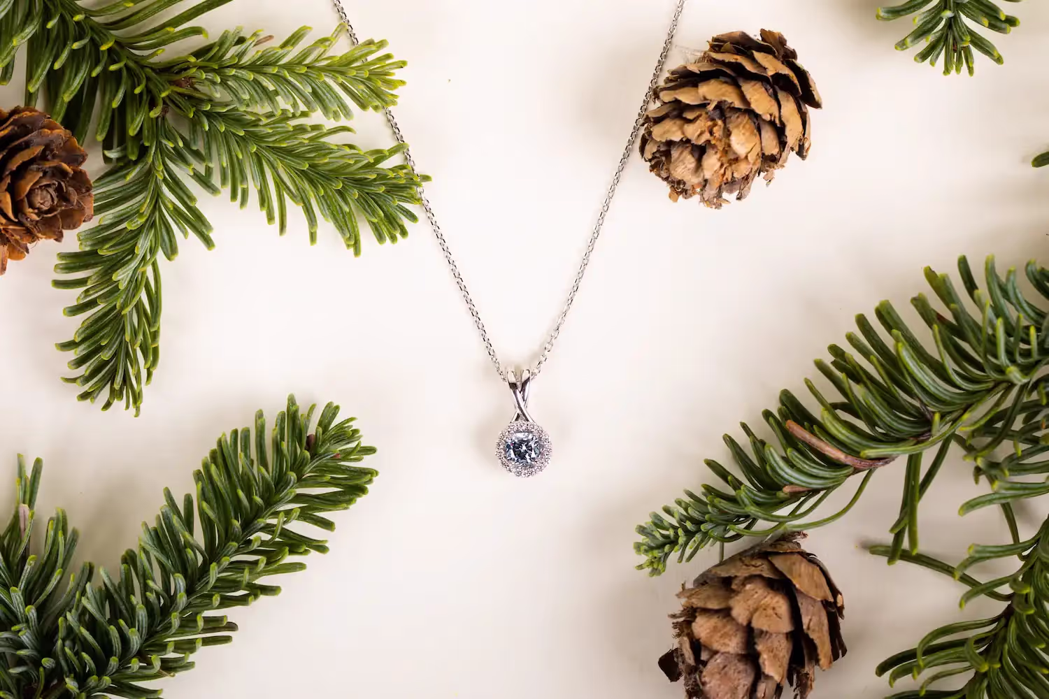 Blue diamond necklace surrounded by pinecones and pine needles.