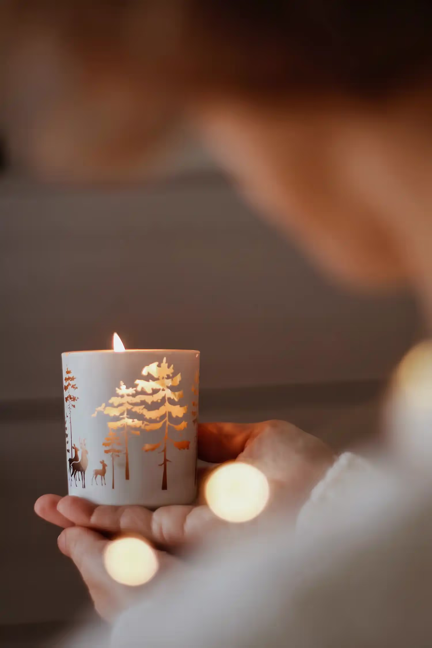 Person holding a lit winter themed candle.