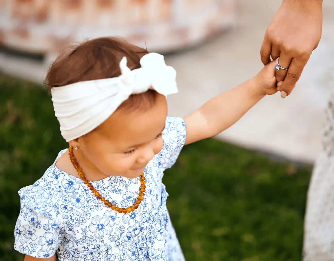 A toddler holding an adult’s hand, with a ring visible.